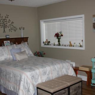 A cozy bedroom with a neatly made bed and decorative elements.