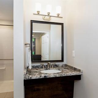 A modern bathroom vanity with a marble countertop and mirror, complemented by overhead lighting.