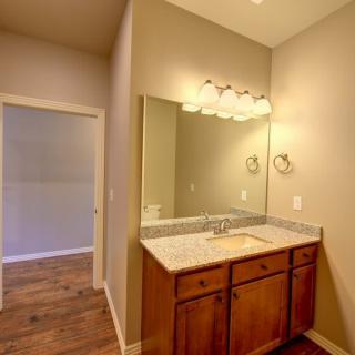 A bathroom featuring a wooden vanity with a large mirror and overhead lighting.
