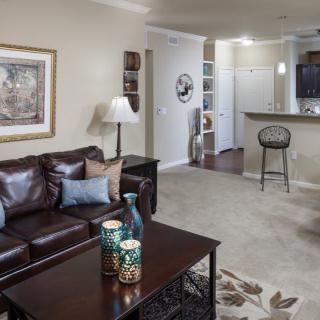 A cozy living room with a leather sofa, coffee table, and open layout leading to the kitchen.