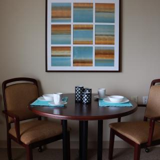 A small dining area with a round table set for two, featuring modern artwork on the wall.
