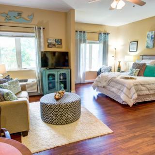 A cozy bedroom with a stylish interior design featuring wood flooring, comfortable seating, and decorative elements.