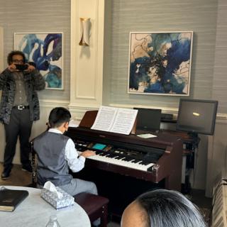 A young pianist performs at an event, showcasing their talent in front of an audience.