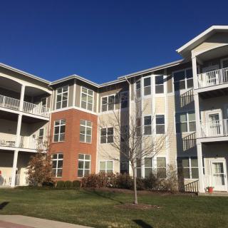 A modern apartment building with a brick facade and multiple balconies under clear blue skies.