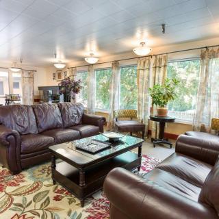 A cozy living room with leather sofas, a coffee table, and large windows allowing ample natural light.