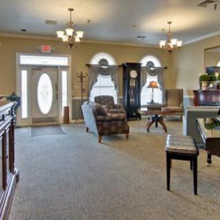 A well-furnished living room featuring comfortable seating, large windows, and elegant chandeliers.