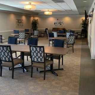 An empty conference room with tables and chairs arranged for a meeting, featuring soft lighting and a piano in the background.