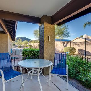 A cozy patio with a small table and two chairs, overlooking a scenic view of mountains and trees.