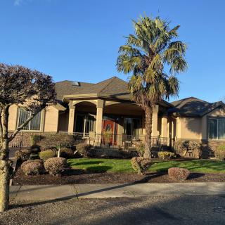 A beautiful house with well-maintained landscaping and a prominent palm tree under a clear blue sky.