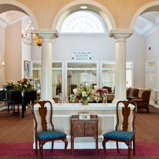 A traditional lobby interior featuring columns, floral arrangements, and classic chairs.