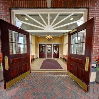 A welcoming entrance with open wooden doors leading into a well-lit interior adorned with a chandelier.