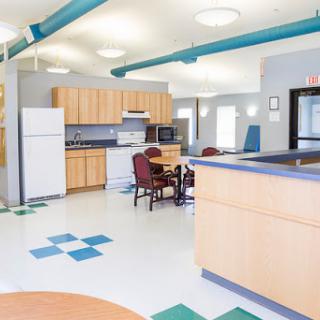 A modern kitchen area featuring wooden cabinets, a refrigerator, and a cozy dining setup.