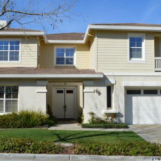 A two-story suburban house with a garage and well-maintained lawn.
