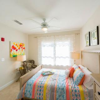 A bright and colorful bedroom with modern decor, featuring a ceiling fan and plenty of natural light.