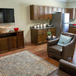 A cozy living area with a kitchenette, featuring leather chairs, a television, and decorative elements.