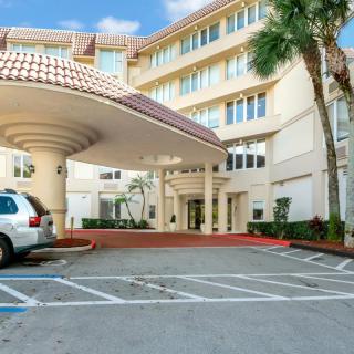 A building entrance with a covered drop-off area and nearby parking spaces.