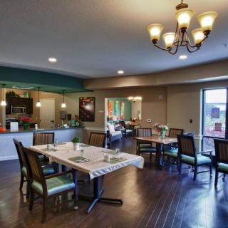 A modern dining room with neatly arranged tables, comfortable chairs, and a decorative chandelier.
