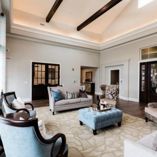 A spacious living room with elegant furniture and high ceilings featuring wooden beams.