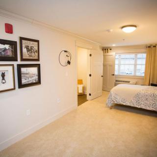 A cozy bedroom with wall art, a neatly made bed, and bright lighting.