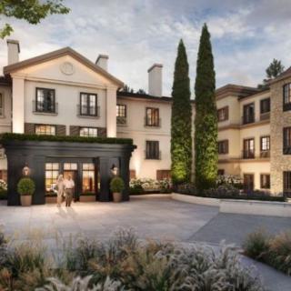 A stylish hotel building with elegant architecture surrounded by lush landscaping and tall trees.