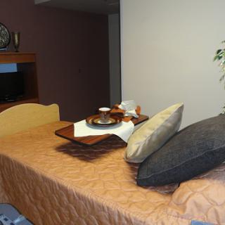 A cozy hotel room featuring a neatly made bed with decorative pillows and a breakfast tray.