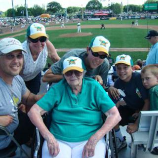 A family group poses for a photo at a baseball game, with one member in a wheelchair.