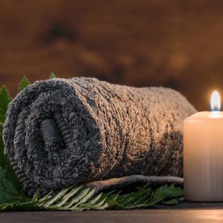 A rolled towel with a lit candle, creating a serene spa atmosphere.