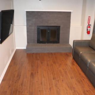 A cozy living room featuring a fireplace, hardwood floors, and a comfortable sofa.