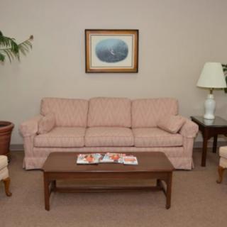 A cozy living room with a pink sofa, coffee table, lamp, and indoor plant.