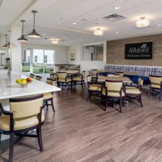 A modern dining area with stylish tables and chairs, adjacent to a kitchen space.