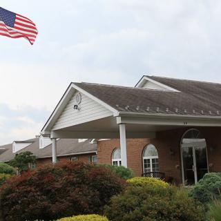 A brick building with an American flag and landscaped entrance.