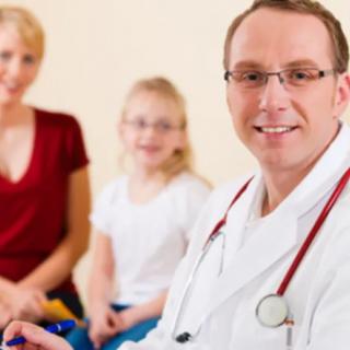 A doctor smiling with a family in a healthcare setting.