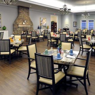 A well-furnished dining room with arranged tables and chairs, featuring a fireplace and chandeliers.