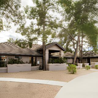 A modern residential home surrounded by trees and neatly landscaped grounds.