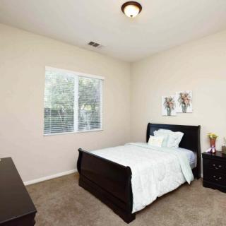 A minimalist bedroom with a single bed, nightstand, and window.