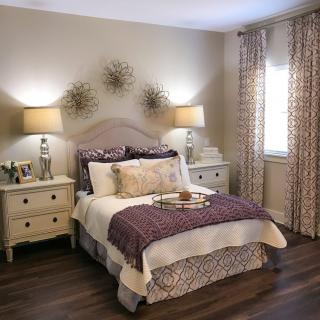 A cozy bedroom with elegant decor, featuring a well-made bed flanked by nightstands and lamps.