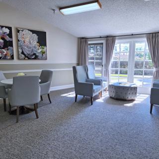 A bright and modern living room with comfortable chairs, a table, and large windows letting in natural light.