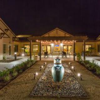 Illuminated building entrance with pathway and decorative pottery at night.