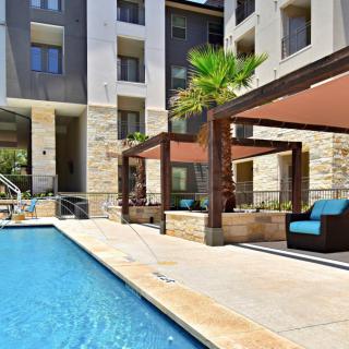 Modern apartment complex with a pool and cozy lounge area.