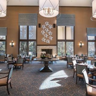 Spacious dining area with elegant chandeliers and large windows, featuring a central fireplace.