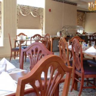 An empty dining room with elegantly set tables and wooden chairs.