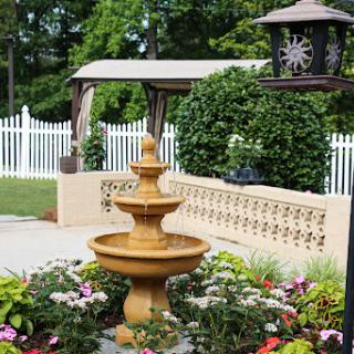A beautiful outdoor garden featuring a charming fountain surrounded by vibrant flowers.