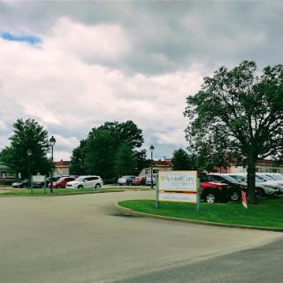 A view of a parking lot surrounded by trees under a cloudy sky.