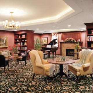 A cozy lounge area featuring a piano, fireplace, and comfortable seating.