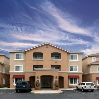 A residential building with parked cars under a partly cloudy sky.