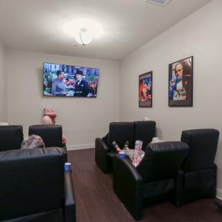 A cozy home theater room with recliner chairs and movie posters on the walls.