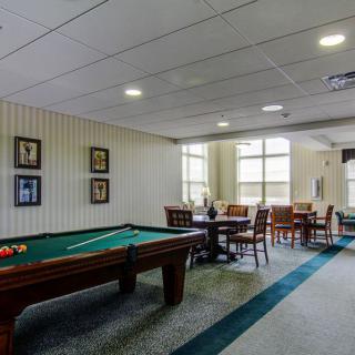 A recreation room featuring a pool table and seating area with tables and chairs.