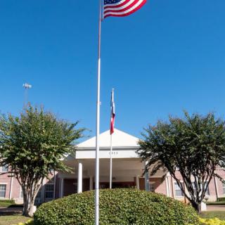 A building entrance with an American flag flying on a sunny day.