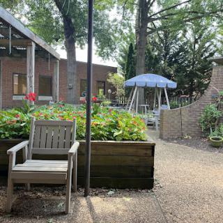 A serene garden patio featuring a comfortable chair, vibrant flowers, and a swing, perfect for relaxation.