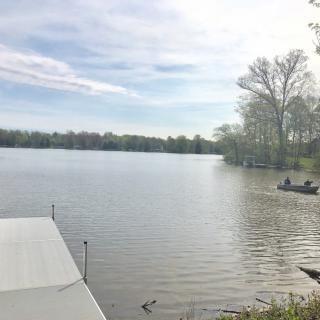 A serene lake view with a boat and surrounding trees under a clear sky.